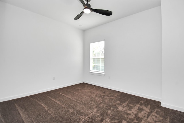 spare room featuring ceiling fan and dark carpet