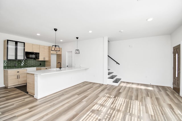 kitchen featuring hanging light fixtures, tasteful backsplash, light brown cabinets, and light hardwood / wood-style flooring