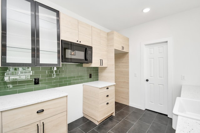 kitchen featuring light stone counters, light brown cabinetry, tasteful backsplash, and dark tile patterned floors