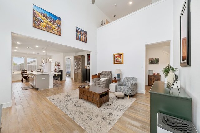 interior space with a high ceiling, sink, heating unit, and light wood-type flooring