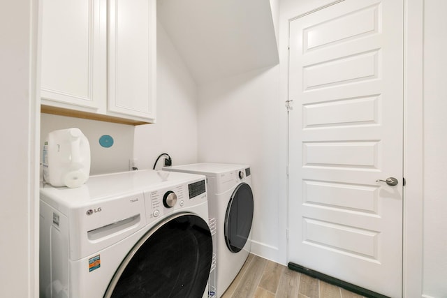 laundry area with cabinets, separate washer and dryer, and light hardwood / wood-style floors