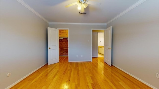 unfurnished bedroom featuring a walk in closet, light hardwood / wood-style flooring, ornamental molding, and a closet