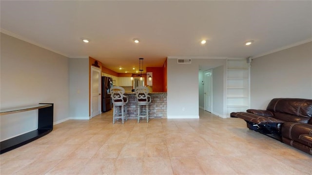 kitchen with ornamental molding, black refrigerator, a breakfast bar area, and decorative light fixtures