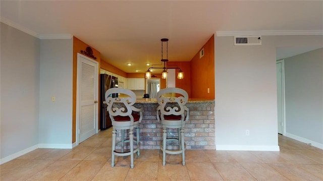 kitchen featuring white cabinetry, a kitchen bar, ornamental molding, kitchen peninsula, and black fridge