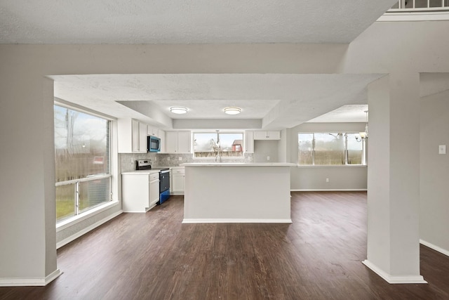 kitchen featuring tasteful backsplash, dark hardwood / wood-style floors, a kitchen island, electric stove, and white cabinets