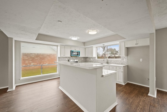 kitchen with backsplash, dark wood-type flooring, a kitchen island, and white cabinets