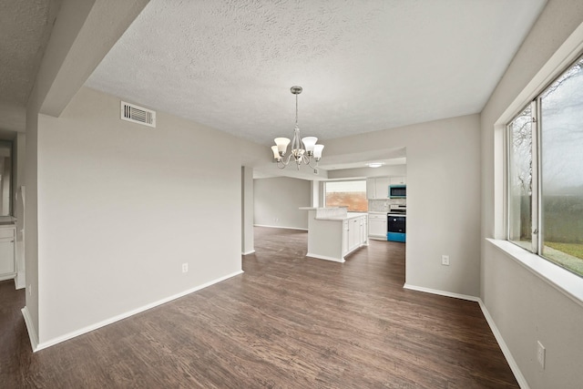 unfurnished dining area featuring dark wood-type flooring, a notable chandelier, and a textured ceiling