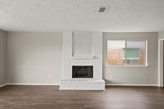 unfurnished living room with dark hardwood / wood-style flooring, a textured ceiling, and a fireplace