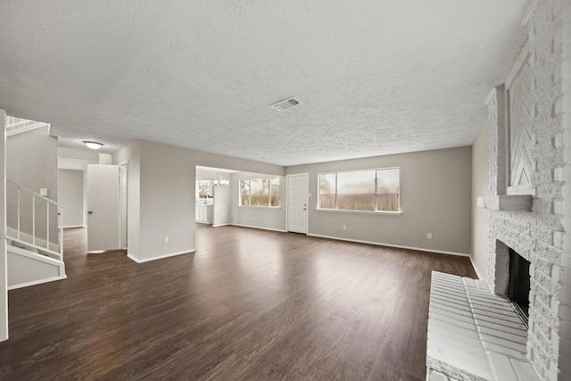 unfurnished living room with dark hardwood / wood-style flooring, a notable chandelier, a fireplace, and a textured ceiling