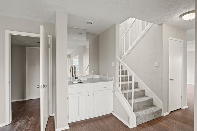 staircase featuring sink, hardwood / wood-style floors, and a textured ceiling