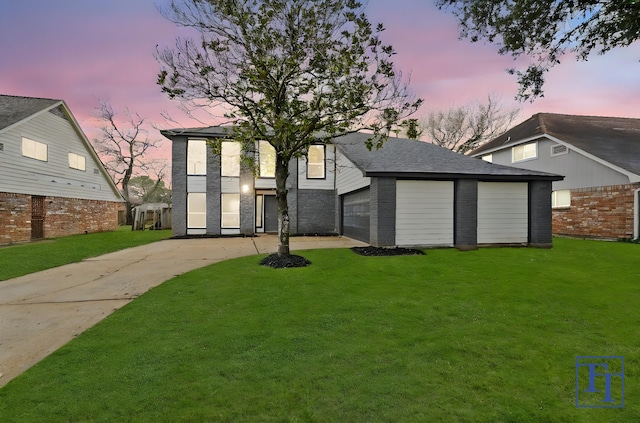 back house at dusk with a garage and a lawn