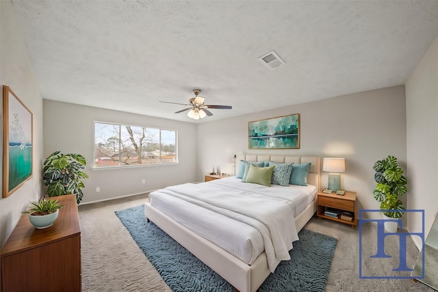 carpeted bedroom with ceiling fan and a textured ceiling