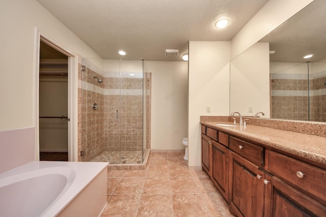 full bathroom featuring tile patterned flooring, vanity, plus walk in shower, a textured ceiling, and toilet