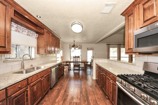 kitchen featuring sink, stainless steel appliances, light stone countertops, dark hardwood / wood-style flooring, and decorative light fixtures