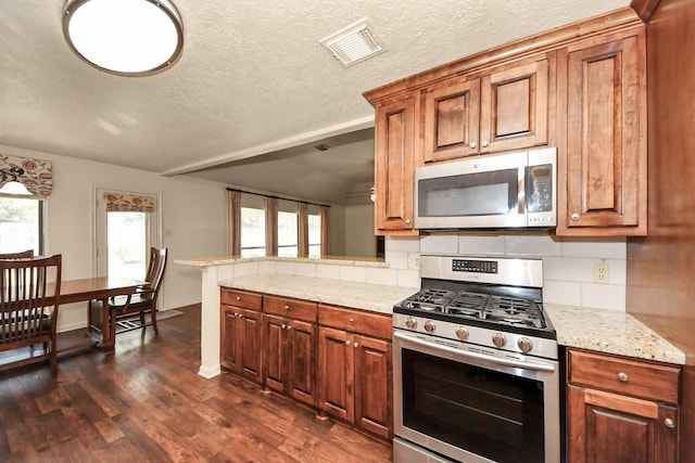 kitchen with stainless steel appliances, tasteful backsplash, dark hardwood / wood-style floors, and light stone counters