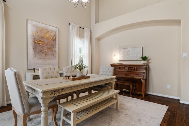 dining space featuring dark wood-type flooring and an inviting chandelier