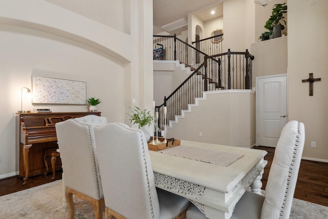 dining area with dark wood-type flooring and a high ceiling