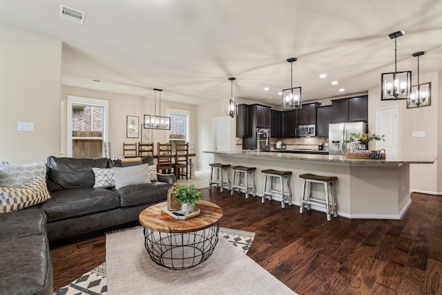 living room featuring dark wood-type flooring, sink, and a notable chandelier