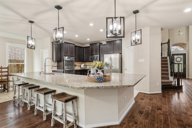 kitchen featuring a breakfast bar area, appliances with stainless steel finishes, a large island, and pendant lighting