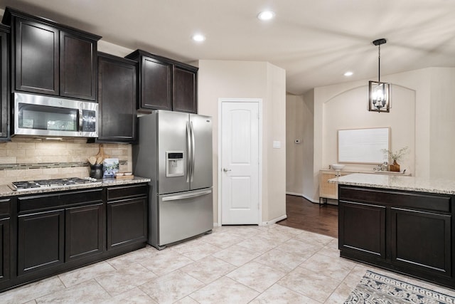 kitchen with tasteful backsplash, stainless steel appliances, light stone countertops, and hanging light fixtures