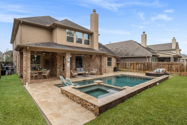 rear view of house with a swimming pool with hot tub, a yard, and a patio