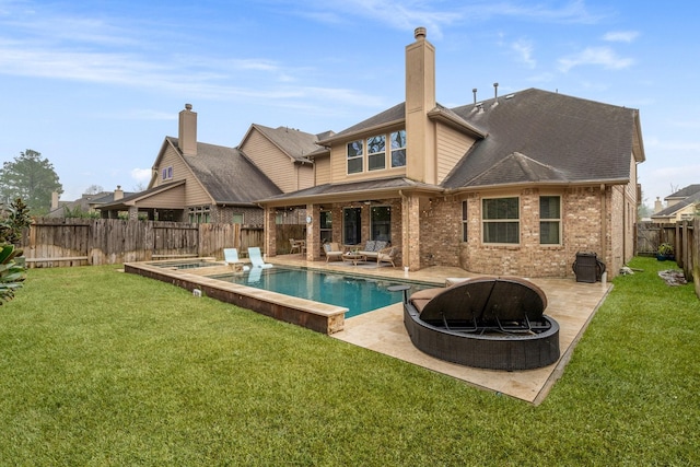 rear view of property with a swimming pool with hot tub, a yard, a fire pit, and a patio