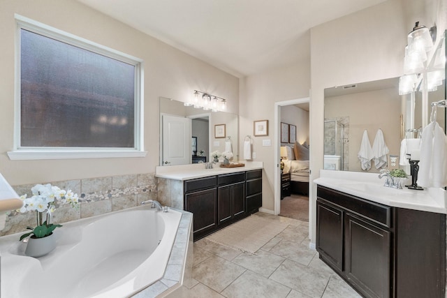 bathroom featuring tile patterned flooring, vanity, and tiled bath