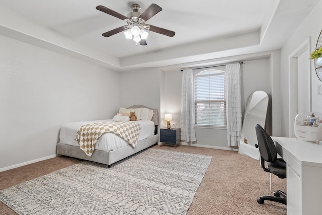 bedroom featuring a raised ceiling, light colored carpet, and ceiling fan