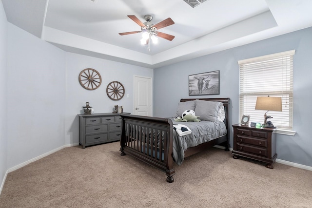 carpeted bedroom featuring ceiling fan and a tray ceiling