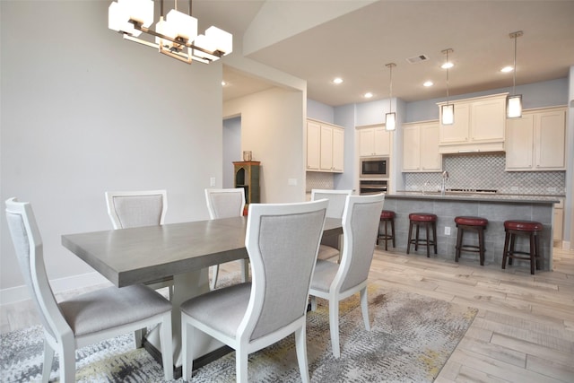 dining space with light wood finished floors, visible vents, baseboards, an inviting chandelier, and recessed lighting