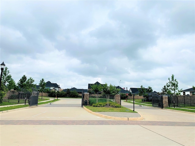 view of road featuring curbs, street lighting, and a gated entry