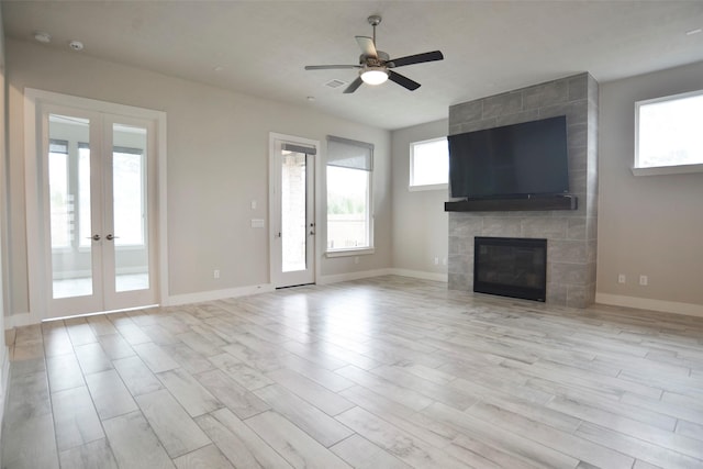 unfurnished living room with light wood-style floors, french doors, a fireplace, and baseboards