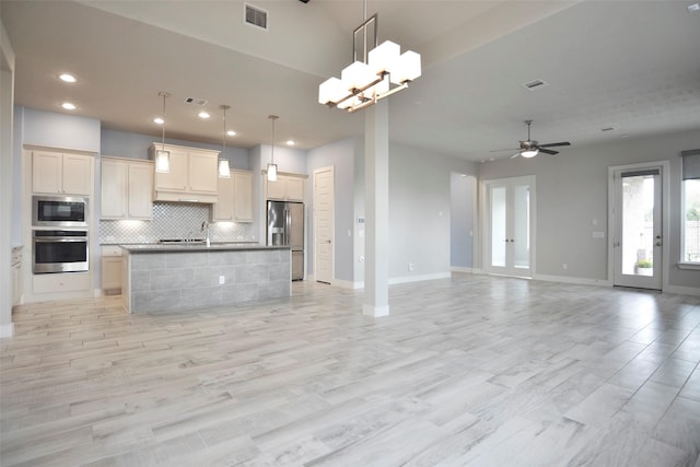 kitchen featuring a kitchen island with sink, visible vents, open floor plan, appliances with stainless steel finishes, and backsplash