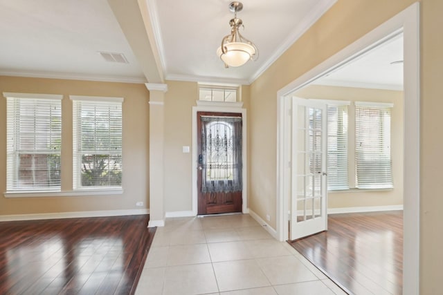 foyer entrance with plenty of natural light, visible vents, crown molding, and baseboards