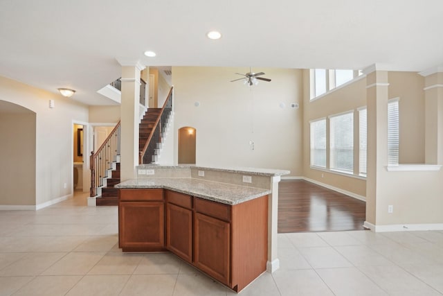 kitchen with brown cabinetry, open floor plan, ceiling fan, and light tile patterned floors