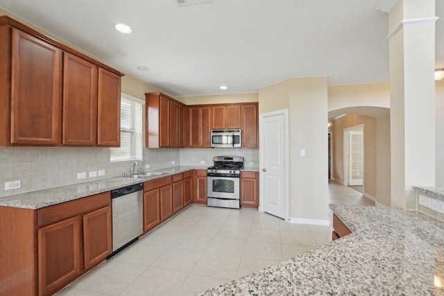 kitchen with light stone counters, recessed lighting, a sink, appliances with stainless steel finishes, and decorative backsplash