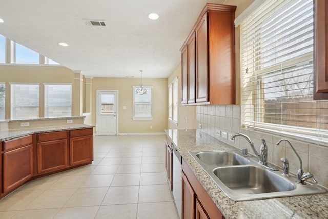 kitchen with light tile patterned floors, hanging light fixtures, backsplash, a sink, and dishwasher