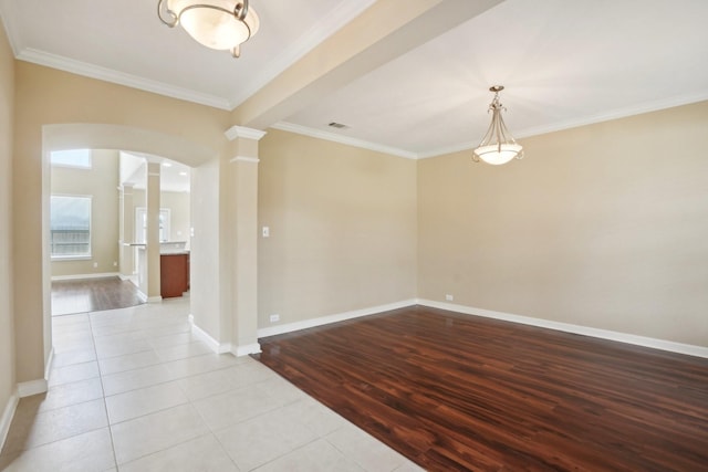 spare room featuring ornate columns, baseboards, ornamental molding, and light tile patterned flooring