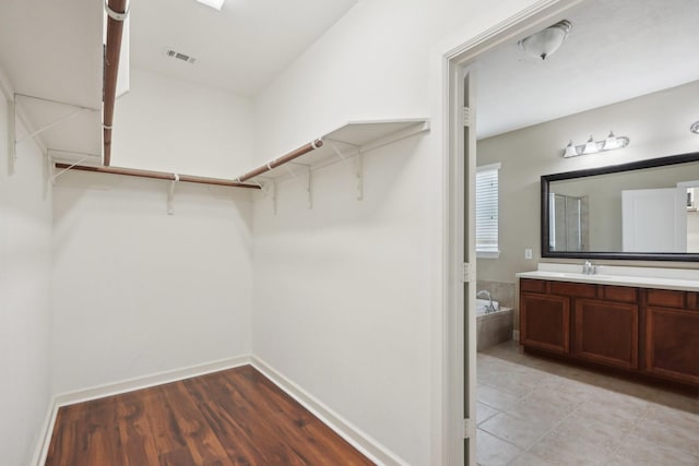 walk in closet featuring visible vents, a sink, and light wood-style flooring