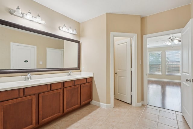 full bath with double vanity, tile patterned flooring, a sink, and baseboards