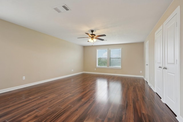 unfurnished room with dark wood-style flooring, visible vents, ceiling fan, and baseboards