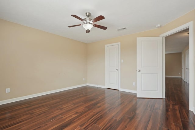 empty room featuring ceiling fan, dark wood-type flooring, visible vents, and baseboards