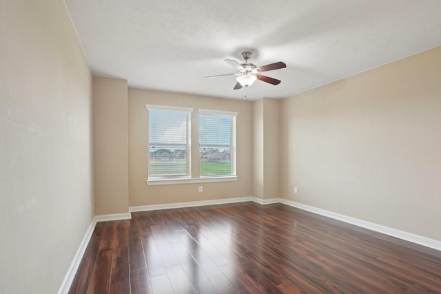 spare room featuring ceiling fan, baseboards, and dark wood-style flooring