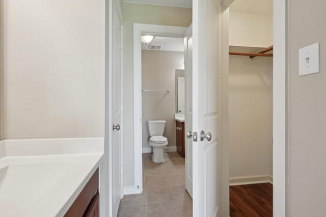 bathroom featuring visible vents, baseboards, tile patterned flooring, a spacious closet, and vanity