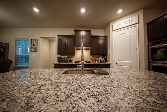15516 Forest Grove Dr, Willis, TX 77378 - kitchen with appliances with stainless steel finishes, light stone countertops, tasteful backsplash, dark brown cabinets, and a sink