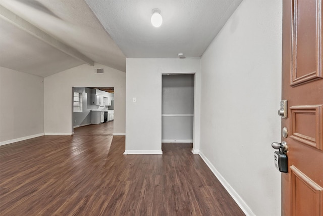 interior space with dark wood-type flooring, lofted ceiling with beams, and a textured ceiling