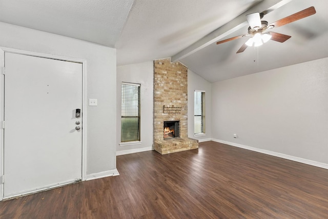 unfurnished living room featuring dark wood-type flooring, vaulted ceiling with beams, a textured ceiling, ceiling fan, and a fireplace