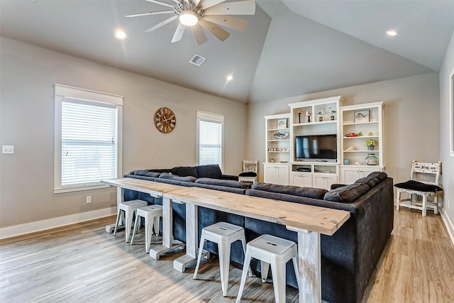 living room featuring ceiling fan, light hardwood / wood-style flooring, high vaulted ceiling, and a healthy amount of sunlight