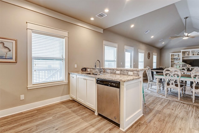 kitchen with a wealth of natural light, white cabinetry, sink, stainless steel dishwasher, and light stone counters