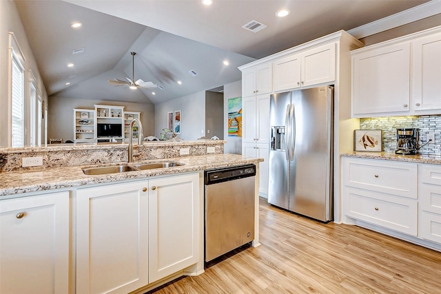 kitchen with sink, light hardwood / wood-style flooring, appliances with stainless steel finishes, white cabinetry, and light stone countertops